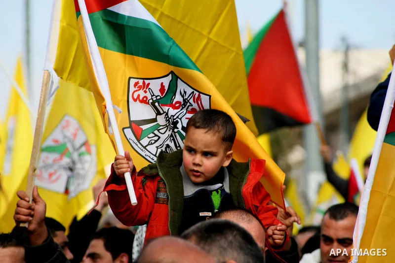 Palestinian supporters of Fatah movement hold national and movement flags during a demonstration in solidarity with Palestinian refugees in Yarmouk refugee camp in the suburbs of the Syrian capital of Damascus, in the We...