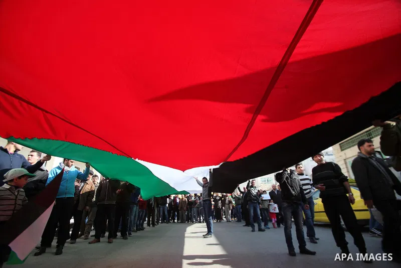 Palestinian supporters of Fatah movement hold national and movement flags during a demonstration in solidarity with Palestinian refugees in Yarmouk refugee camp in the suburbs of the Syrian capital of Damascus, in the We...