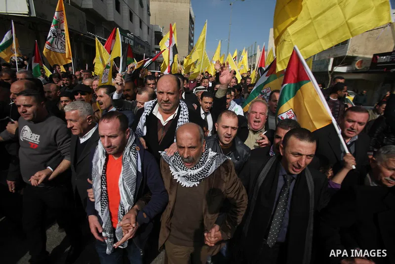 Palestinian supporters of Fatah movement hold national and movement flags during a demonstration in solidarity with Palestinian refugees in Yarmouk refugee camp in the suburbs of the Syrian capital of Damascus, in the We...
