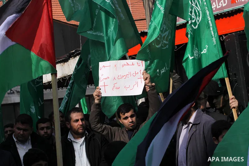 Palestinian supporters of Hamas movement hold national and movement flags during a demonstration in solidarity with Palestinian refugees in Yarmouk refugee camp in the suburbs of the Syrian capital of Damascus, in Gaza C...