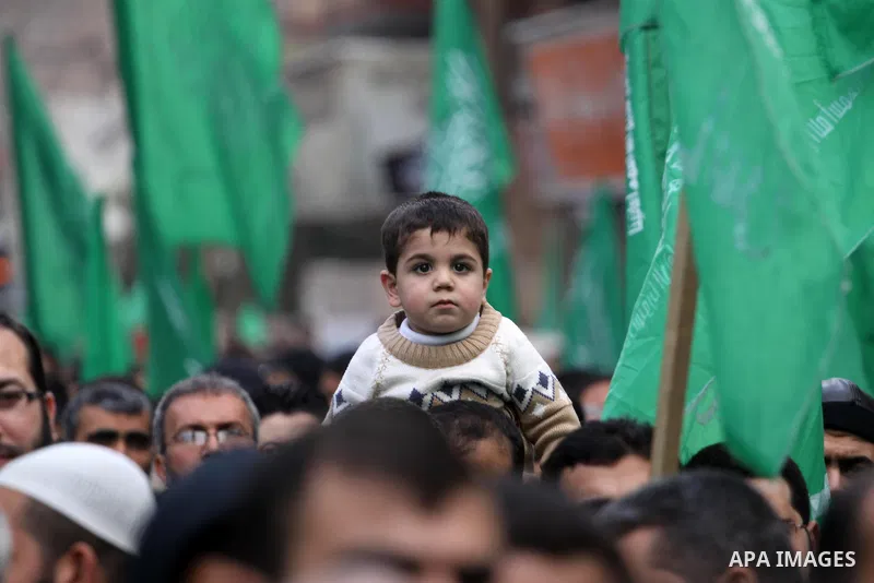 Palestinian supporters of Hamas movement hold national and movement flags during a demonstration in solidarity with Palestinian refugees in Yarmouk refugee camp in the suburbs of the Syrian capital of Damascus, in Gaza C...
