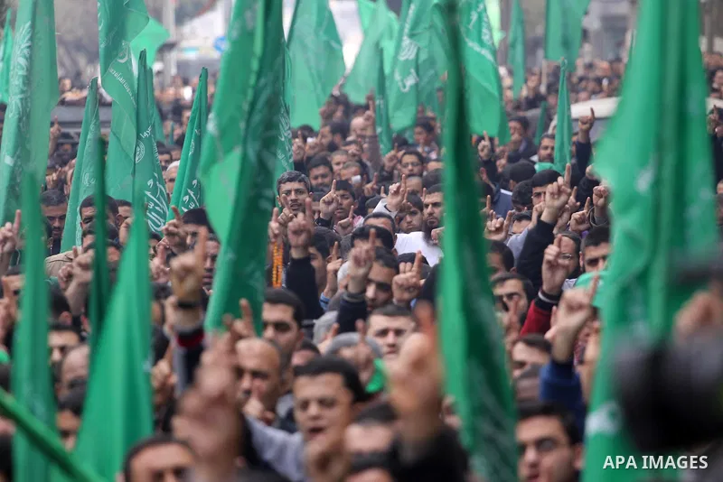 Palestinian supporters of Hamas movement hold national and movement flags during a demonstration in solidarity with Palestinian refugees in Yarmouk refugee camp in the suburbs of the Syrian capital of Damascus, in Gaza C...