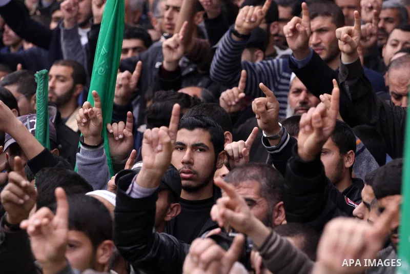 Palestinian supporters of Hamas movement hold national and movement flags during a demonstration in solidarity with Palestinian refugees in Yarmouk refugee camp in the suburbs of the Syrian capital of Damascus, in Gaza C...