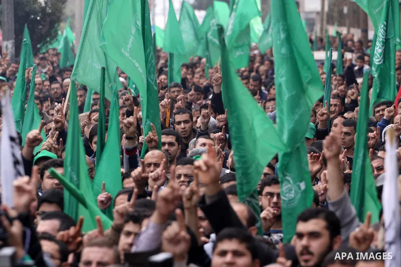 Palestinian supporters of Hamas movement hold national and movement flags during a demonstration in solidarity with Palestinian refugees in Yarmouk refugee camp in the suburbs of the Syrian capital of Damascus, in Gaza C...