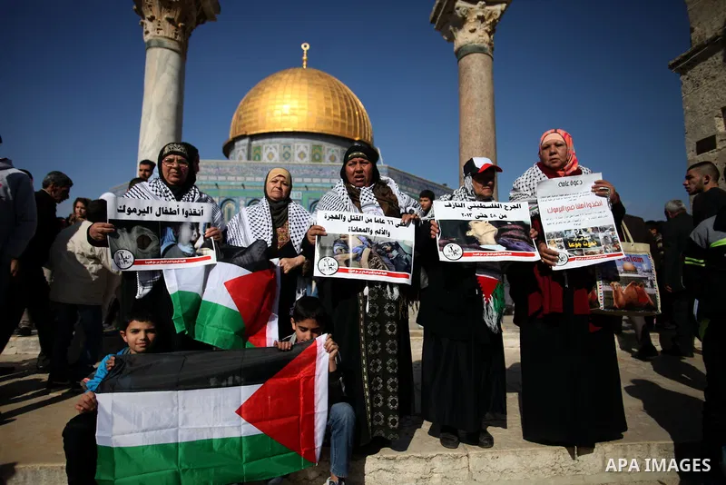 Palestinian worshipers hold placards during a protest in solidarity with Palestinian refugees in Yarmouk camp in Syria who are living in low conditions and under the siege, following Friday prayers at the Al-Aqsa compoun...