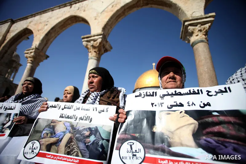 Palestinian worshipers hold placards during a protest in solidarity with Palestinian refugees in Yarmouk camp in Syria who are living in low conditions and under the siege, following Friday prayers at the Al-Aqsa compoun...
