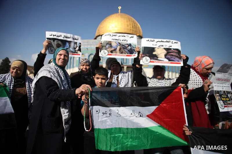 Palestinian worshipers hold placards during a protest in solidarity with Palestinian refugees in Yarmouk camp in Syria who are living in low conditions and under the siege, following Friday prayers at the Al-Aqsa compoun...