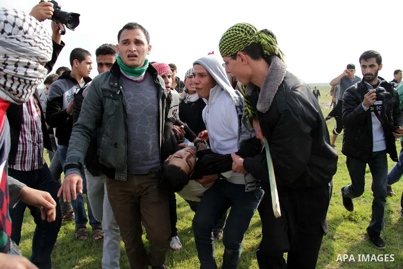Palestinians carry a fellow protester wounded during clashes with Israeli forces near the Nahal Oz border crossing with Israel, east of Gaza City on January 17, 2014. The Israeli army fired live rounds and tear gas at pr...
