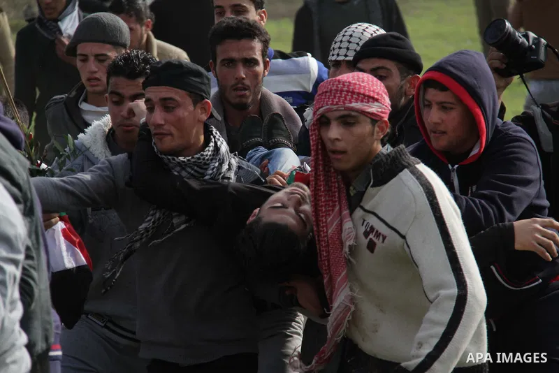 Palestinians carry a fellow protester wounded during clashes with Israeli forces near the Nahal Oz border crossing with Israel, east of Gaza City on January 17, 2014. The Israeli army fired live rounds and tear gas at pr...