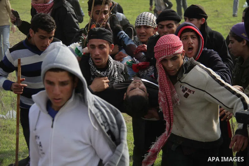 Palestinians carry a fellow protester wounded during clashes with Israeli forces near the Nahal Oz border crossing with Israel, east of Gaza City on January 17, 2014. The Israeli army fired live rounds and tear gas at pr...