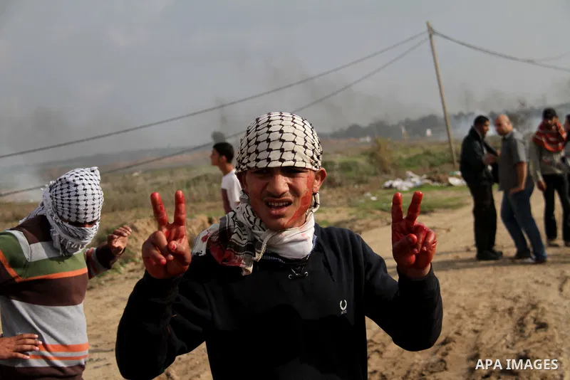 A Palestinian protester flashes a victory sign with his bloody hand during clashes with Israeli forces near the Nahal Oz border crossing with Israel, east of Gaza City on January 17, 2014. The Israeli army fired live rou...