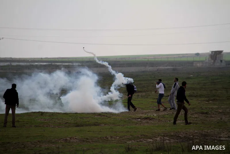 Palestinians throw back tear gas canister during clashes with Israeli forces near the Nahal Oz border crossing with Israel, east of Gaza City on January 17, 2014. The Israeli army fired live rounds and tear gas at protes...