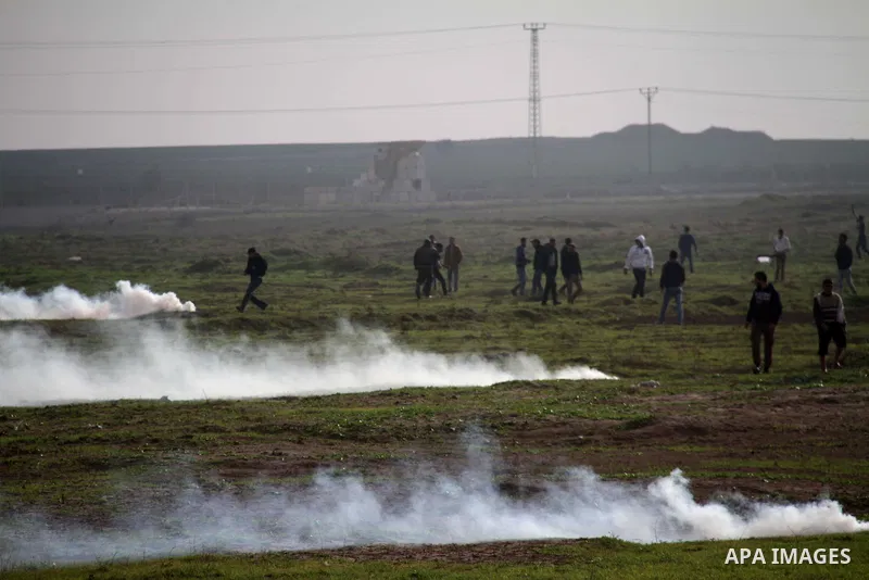 Palestinian protesters run away from tear gas fired by Israeli security forces during clashes near the Nahal Oz border crossing with Israel, east of Gaza City on January 17, 2014. The Israeli army fired live rounds and t...