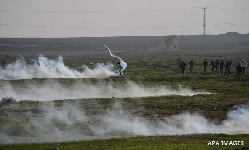 Palestinians throw back tear gas canister during clashes with Israeli forces near the Nahal Oz border crossing with Israel, east of Gaza City on January 17, 2014. The Israeli army fired live rounds and tear gas at protes...