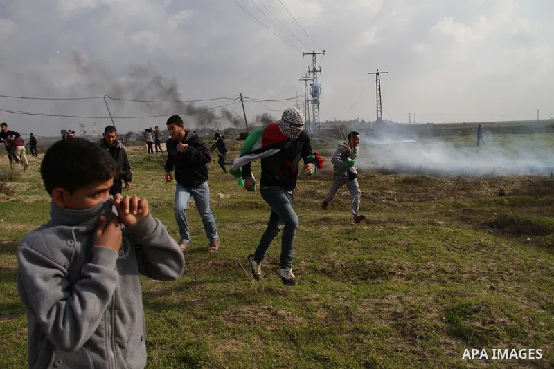 Palestinian protesters run away from tear gas fired by Israeli security forces during clashes near the Nahal Oz border crossing with Israel, east of Gaza City on January 17, 2014. The Israeli army fired live rounds and t...