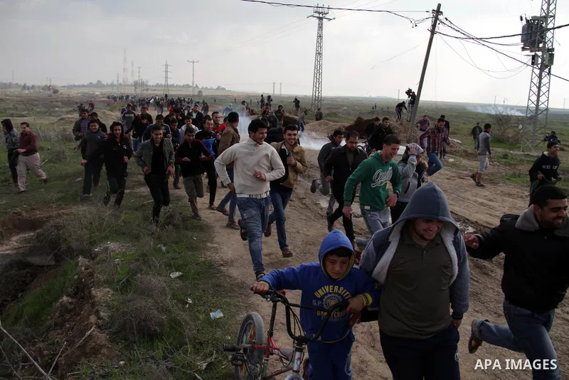 Palestinian protesters run away from tear gas fired by Israeli security forces during clashes near the Nahal Oz border crossing with Israel, east of Gaza City on January 17, 2014. The Israeli army fired live rounds and t...