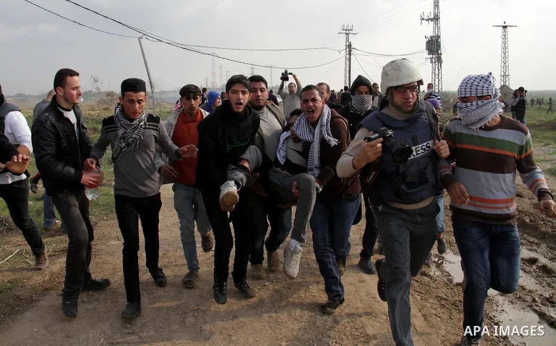 Palestinians carry a fellow protester wounded during clashes with Israeli forces near the Nahal Oz border crossing with Israel, east of Gaza City on January 17, 2014. The Israeli army fired live rounds and tear gas at pr...