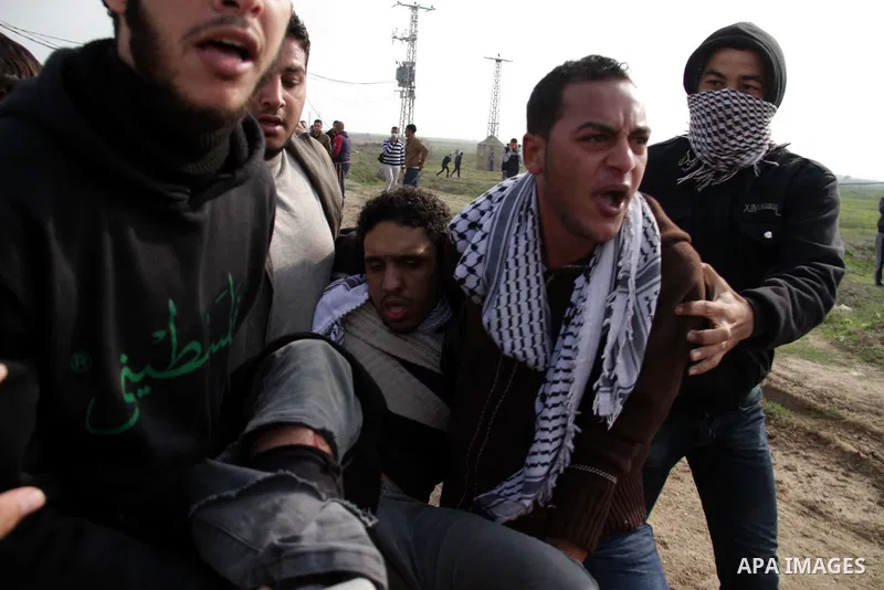 Palestinians carry a fellow protester wounded during clashes with Israeli forces near the Nahal Oz border crossing with Israel, east of Gaza City on January 17, 2014. The Israeli army fired live rounds and tear gas at pr...