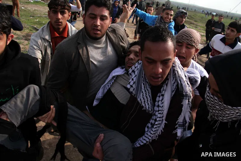 Palestinians carry a fellow protester wounded during clashes with Israeli forces near the Nahal Oz border crossing with Israel, east of Gaza City on January 17, 2014. The Israeli army fired live rounds and tear gas at pr...