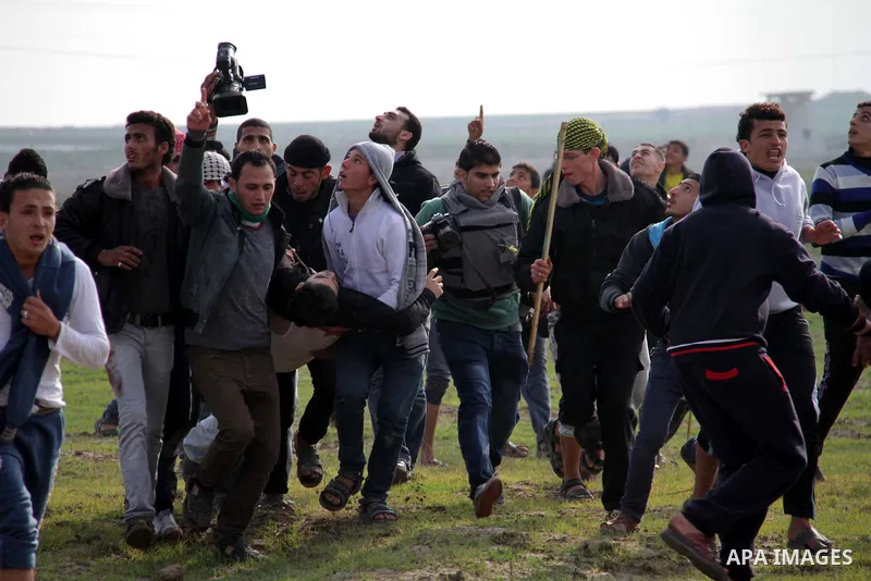 Palestinians carry a fellow protester wounded during clashes with Israeli forces near the Nahal Oz border crossing with Israel, east of Gaza City on January 17, 2014. The Israeli army fired live rounds and tear gas at pr...