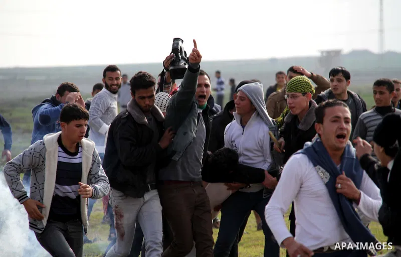 Palestinians carry a fellow protester wounded during clashes with Israeli forces near the Nahal Oz border crossing with Israel, east of Gaza City on January 17, 2014. The Israeli army fired live rounds and tear gas at pr...