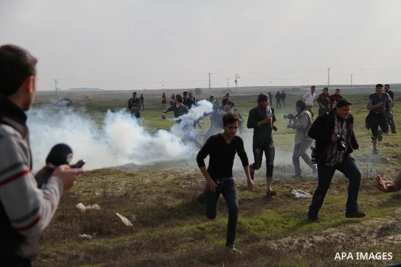 Palestinian protesters run away from tear gas fired by Israeli security forces during clashes near the Nahal Oz border crossing with Israel, east of Gaza City on January 17, 2014. The Israeli army fired live rounds and t...