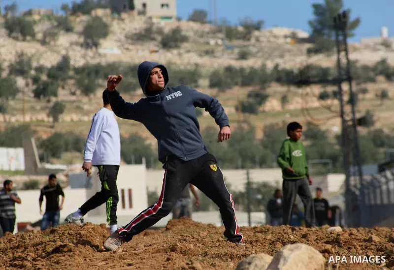 Palestinians throw stones towards Israeli security forces to protest against the demolition of a furniture factory which Israelis said was built without a permit on January 20, 2014 in the village of Deir Samet near the...