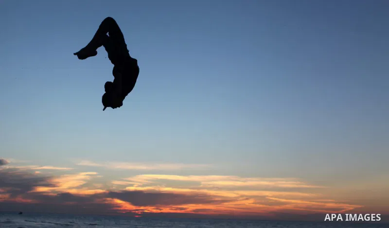 A Palestinian youth performs stunts at the beach of Gaza City with his friends during sunset January 20, 2014. Photo by Ashraf Amra