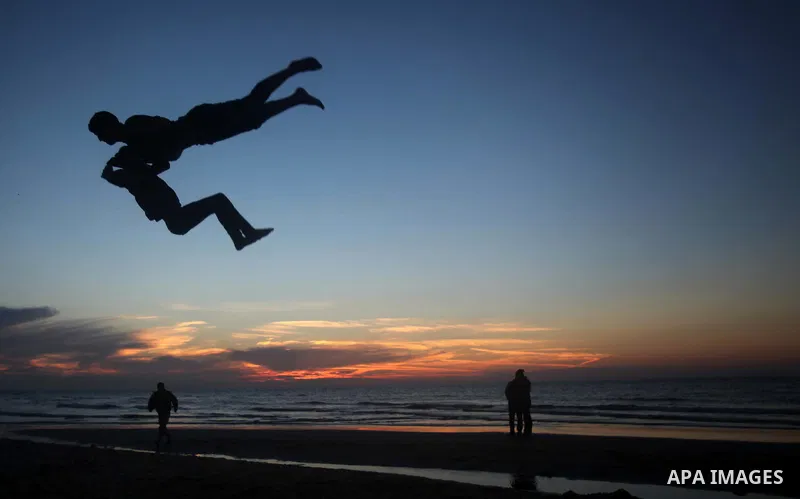 Palestinian youths perform stunts at the beach of Gaza City with their friends during sunset January 20, 2014. Photo by Ashraf Amra