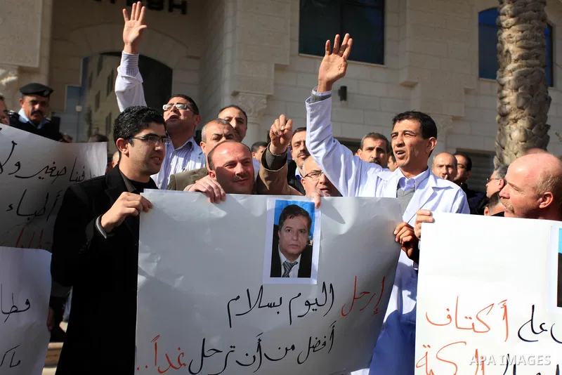 Palestinian doctors and employees of the Health ministry hold placards during a protest calling for the dismissal of the Minister of Health, in front of the supreme judicial council in the West Bank City of Ramallah Janu...
