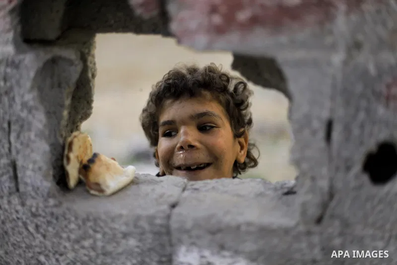 A Palestinian boy looks on behined a wall as he plays outside his family's house at al-Shati refugee camp in the west Gaza City January 22, 2014. Photo by Emad Nassar