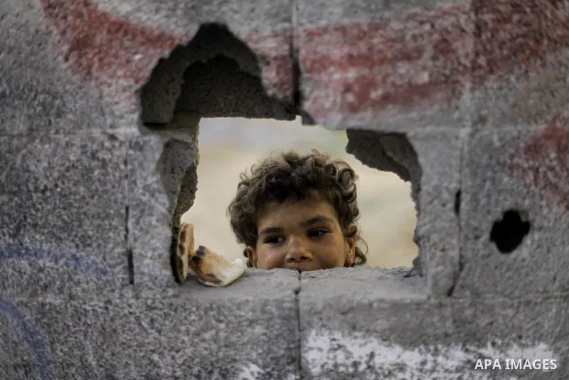 A Palestinian boy looks on behined a wall as he plays outside his family's house at al-Shati refugee camp in the west Gaza City January 22, 2014. Photo by Emad Nassar