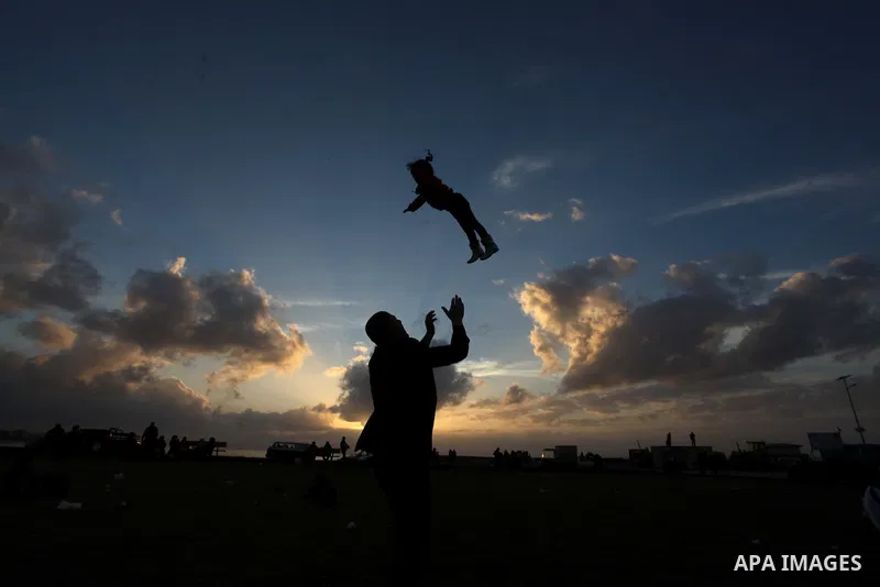 A Palestinian man holds his daughter up in the air during the sunset along the seafront in Gaza City, on January 23, 2014. Israeli Prime Minister Benjamin Netanyahu threatened Tuesday to teach Gaza's ruling Hamas movemen...