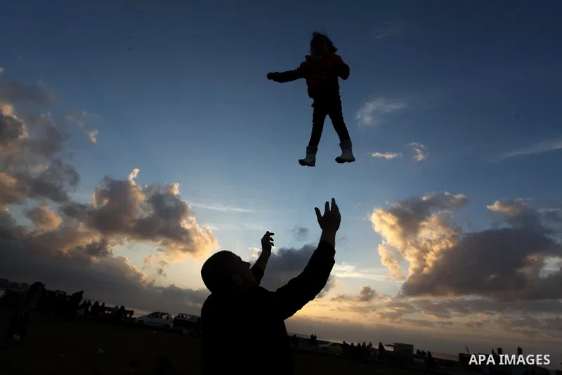 A Palestinian man holds his daughter up in the air during the sunset along the seafront in Gaza City, on January 23, 2014. Israeli Prime Minister Benjamin Netanyahu threatened Tuesday to teach Gaza's ruling Hamas movemen...
