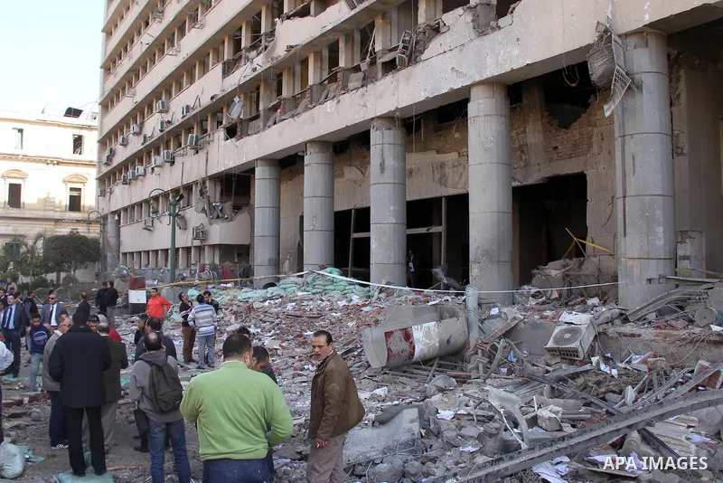 Egyptians inspect the site of a car bomb explosion outside the police headquarters in Cairo on January 24, 2014. A suicide bomber struck Cairo police headquarters in the first of three bombings in the Egyptian capital th...