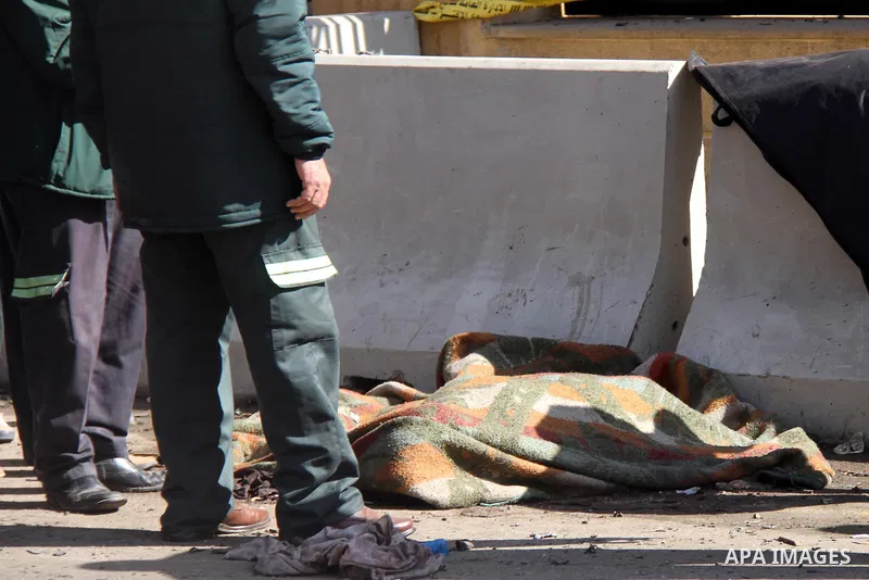 Egyptian security forces stand next to a body of a died man at the site of a car bomb explosion outside the police headquarters in Cairo on January 24, 2014. A suicide bomber struck Cairo police headquarters in the first...