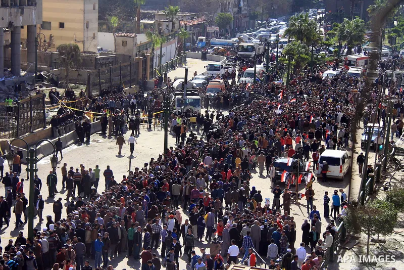 Egyptians inspect the site of a car bomb explosion outside the police headquarters in Cairo on January 24, 2014. A suicide bomber struck Cairo police headquarters in the first of three bombings in the Egyptian capital th...