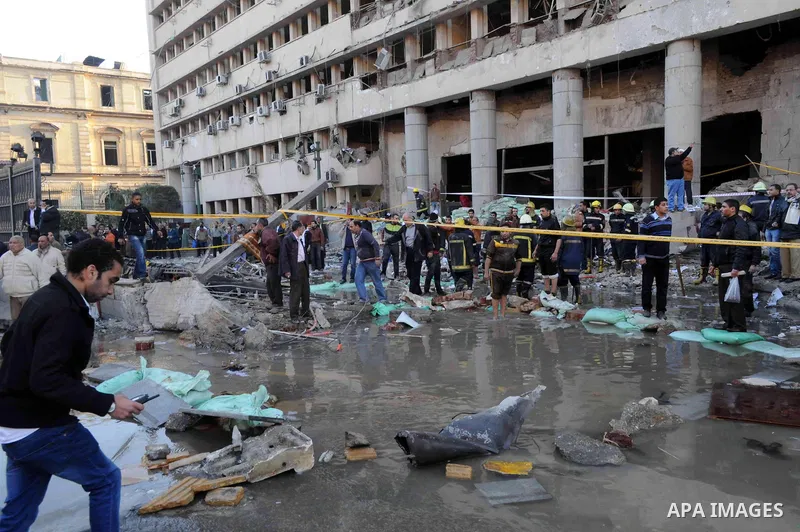 Egyptians inspect the site of a car bomb explosion outside the police headquarters in Cairo on January 24, 2014. A suicide bomber struck Cairo police headquarters in the first of three bombings in the Egyptian capital th...