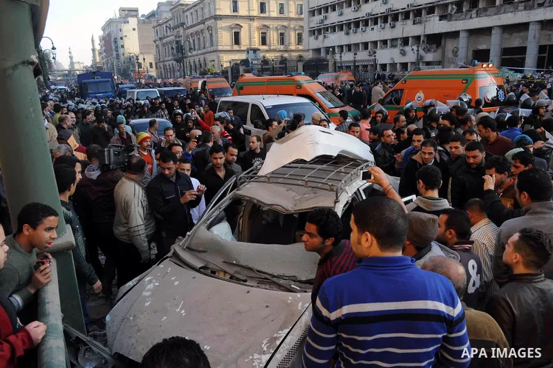 Egyptians inspect the site of a car bomb explosion outside the police headquarters in Cairo on January 24, 2014. A suicide bomber struck Cairo police headquarters in the first of three bombings in the Egyptian capital th...