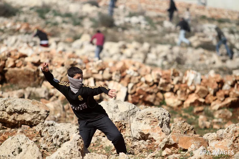 A Palestinian protester throws stones at Israeli security forces during clashes at a protest against Jewish settlements, in the West Bank village of Nabi Saleh, near Ramallah January 24, 2014. Photo by Issam Rimawi