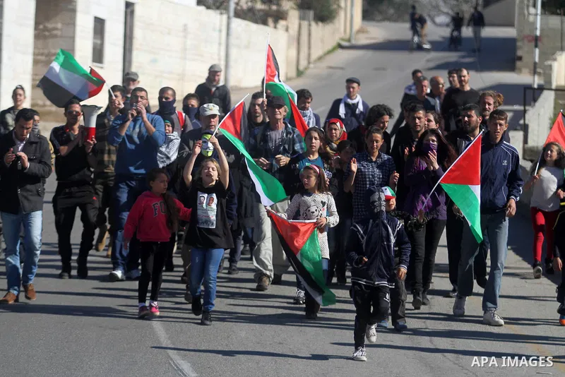 Protesters hold the Palestinian flag during a protest against Jewish settlements, in the West Bank village of Nabi Saleh, near Ramallah January 24, 2014. Photo by Issam Rimawi