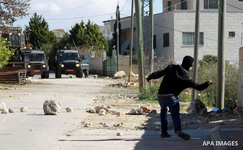 A Palestinian protester throws stones at Israeli security forces as clashes broke out during a demonstration against the expropriation of Palestinian land by Israel in the village of Kfar Qaddum, near the occupied West B...