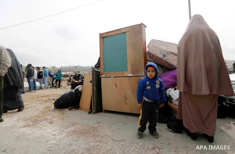Palestinians stand next to their furniture as bulldozers demolish their house in the the Beit Hanina neighborhood of East Jerusalem, January 27, 2014. Israeli authorities on Monday demolished four Palestinian homes in an...