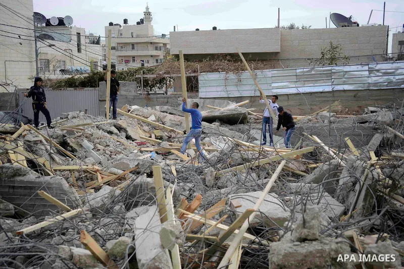 Palestinian search the rubbles following the demolition of their house by israeli police in the the Beit Hanina neighborhood of East Jerusalem, January 27, 2014. Israeli authorities on Monday demolished four Palestinian...