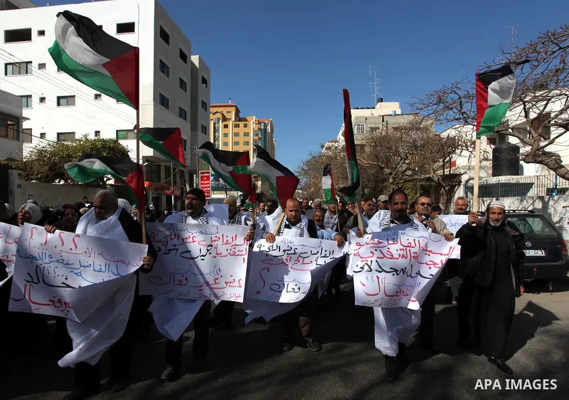 Palestinian families of martyrs who were killed and those that have been wounded in the Israeli-Palestinian conflict in 2008 and 2012, hold placards during a protest against the continued cut of their salaries, in Gaza C...
