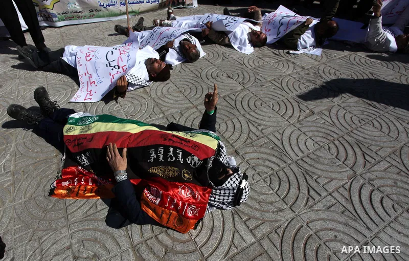 Palestinian families of martyrs who were killed and those that have been wounded in the Israeli-Palestinian conflict in 2008 and 2012, hold placards during a protest against the continued cut of their salaries, in Gaza C...