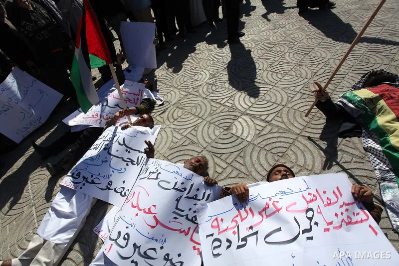 Palestinian families of martyrs who were killed and those that have been wounded in the Israeli-Palestinian conflict in 2008 and 2012, hold placards during a protest against the continued cut of their salaries, in Gaza C...