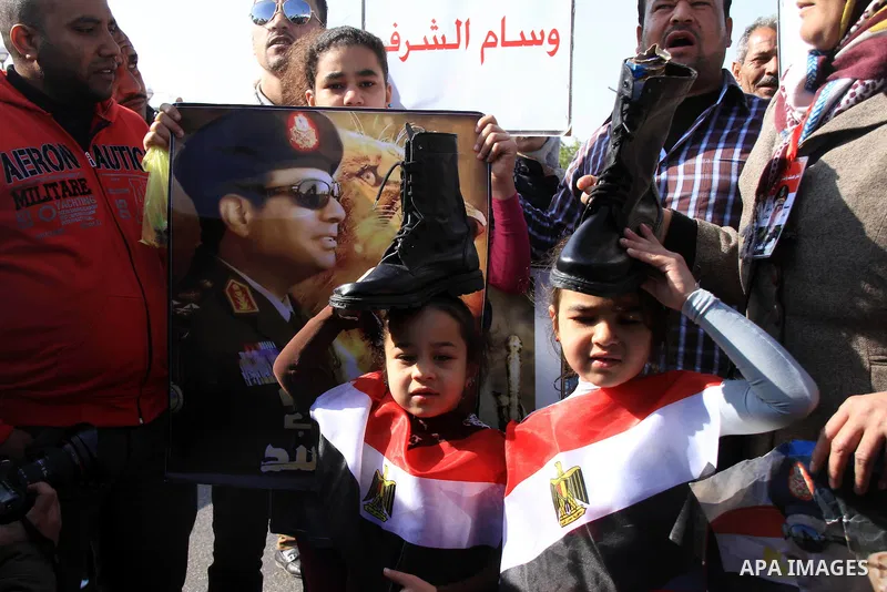 Supporters of Egypt's army chief Field Marshal Abdel Fattah al-Sisi hold military boots on their head as a sign of support for military rule, during a demonstration outside a police academy on the outskirts of Cairo Janu...