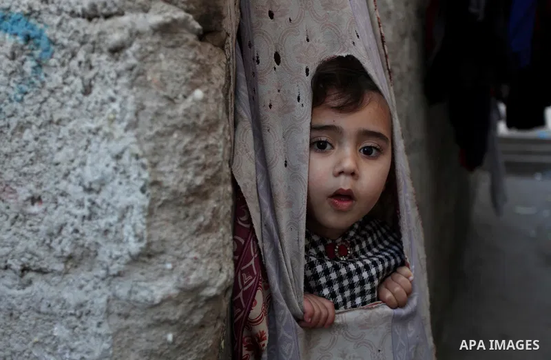 A Palestinian girl looks through a curtain as she plays in front her Family's house at al-Shati refugee camp in the west Gaza City January 29, 2014. Photo by Ashraf Amra