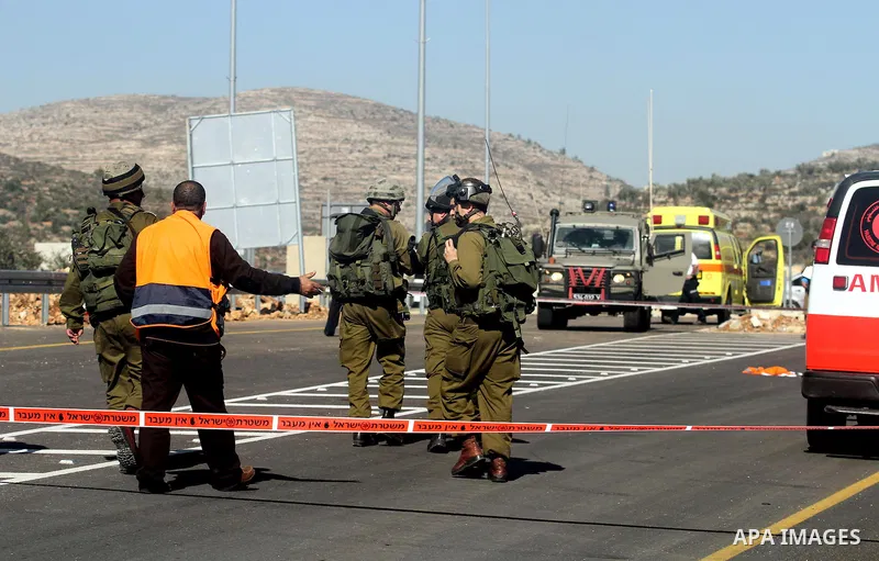 A Palestinian medic man speaks with Israeli soldiers as they guard near the site of a fatal shooting incident next to the Palestinian village of Ein Sariya, north of the West Bank city of Ramallah January 29, 2014. Israe...